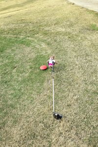 Tedwina trying to lift a golf club.